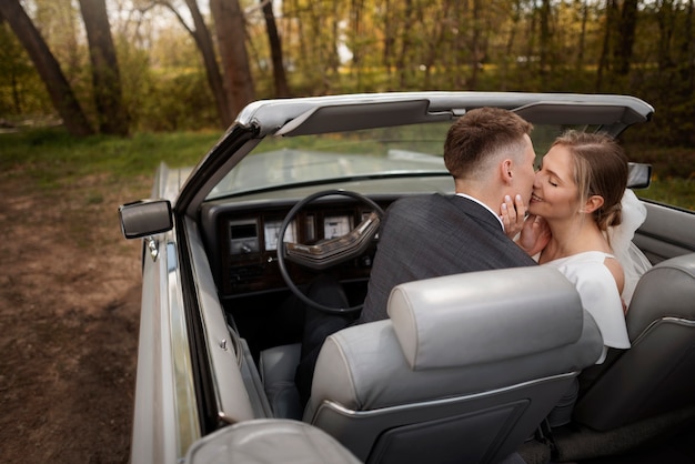 Foto pareja de recién casados con su coche