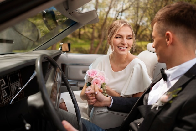 Foto pareja de recién casados con su coche