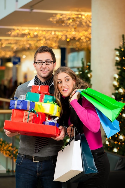 Pareja con regalos de Navidad y bolsas en el centro comercial