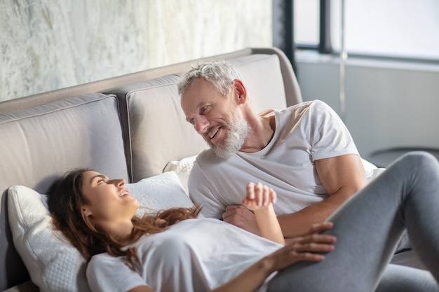 Pareja, relación. Sonriendo mirando el uno al otro hombre y mujer acostada en la cama en casa comunicando