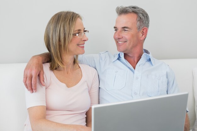 Pareja relajada usando la computadora portátil en casa