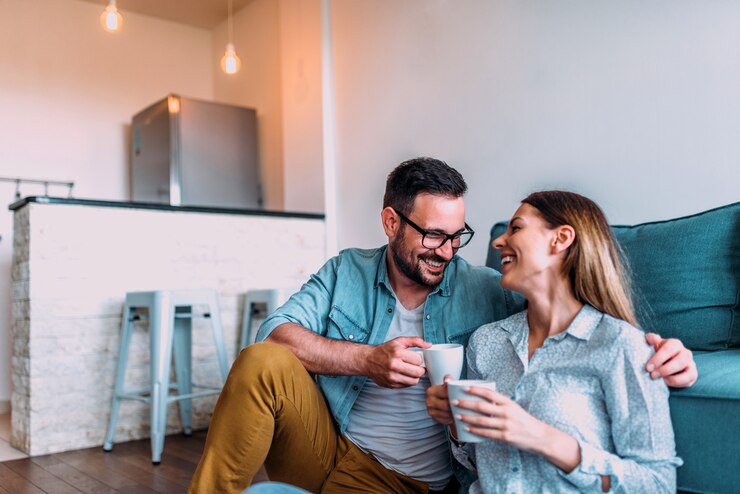 Foto pareja relajándose en casa, tomando café o té mientras está sentado en el piso.