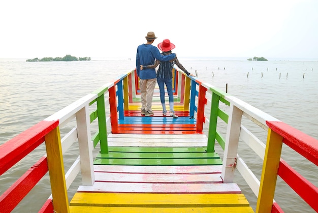 Pareja relajándose juntos en el colorido paseo marítimo de madera frente al mar