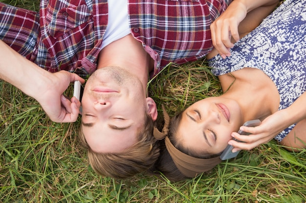 Pareja relajante en el parque en sus teléfonos