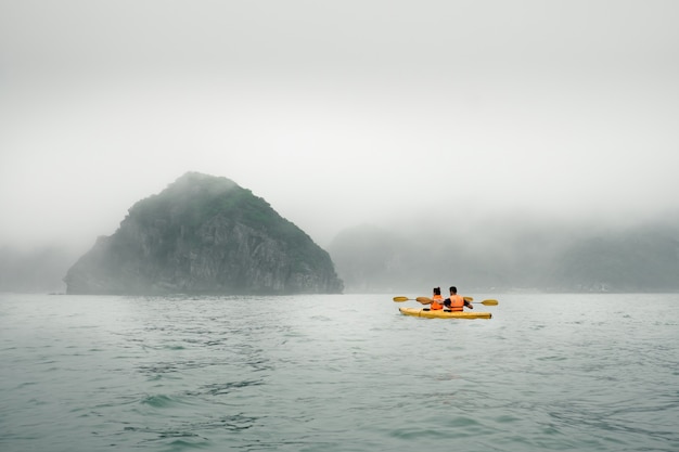 Pareja remando el kayak en tiempo brumoso