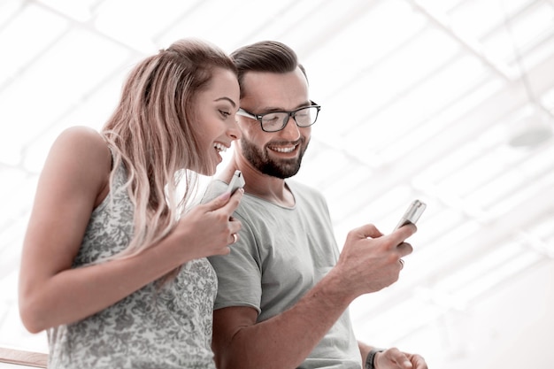 Foto pareja riendo viendo fotos en el teléfono inteligente