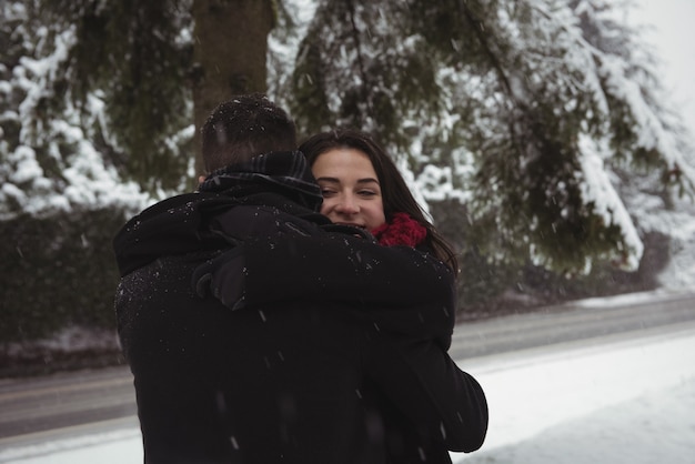 Pareja romántica abrazándose en el bosque durante el invierno