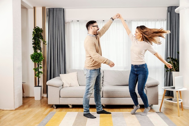 Una pareja romántica bailando juntos en su acogedora casa y divirtiéndose