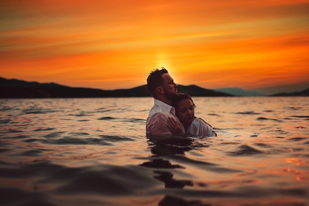 Pareja romántica besándose en el mar al atardecer Foto de alta calidad