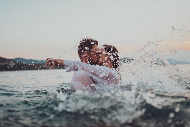 Pareja romántica besándose en el mar al atardecer Foto de alta calidad