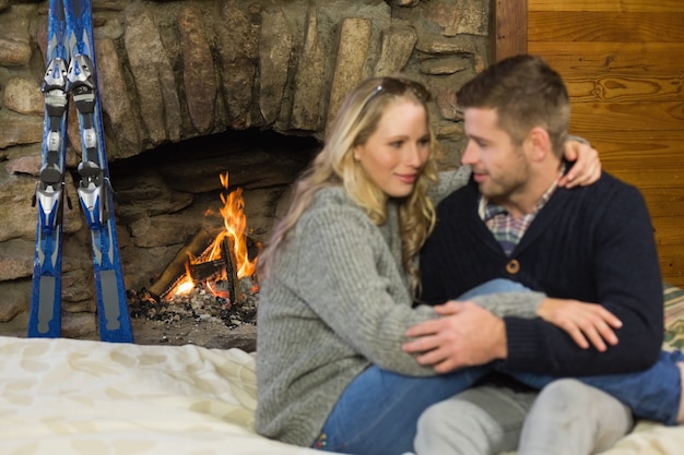 Pareja romántica con los brazos en frente de la chimenea encendida