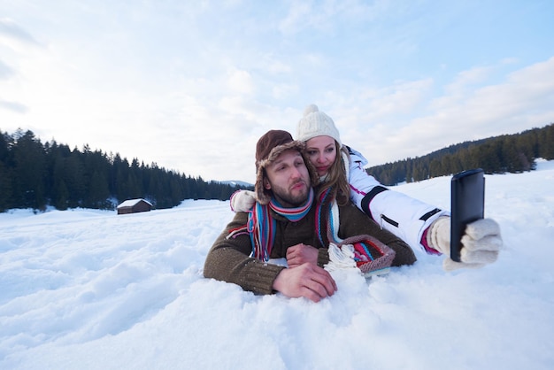 Una pareja romántica se divierten en la nieve fresca y se toman selfies.