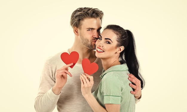 Pareja romántica enamorada abrazo Hombre guapo sin afeitar y linda chica enamorada Día de San Valentín y amor Concepto de sentimientos románticos Pareja de hombre y mujer enamorados tienen tarjeta de corazón rojo sobre fondo blanco