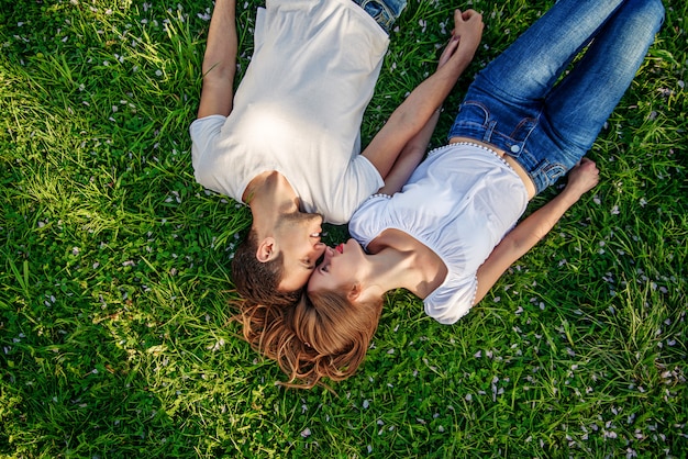 Pareja romántica de jóvenes tumbados en la hierba en el parque.