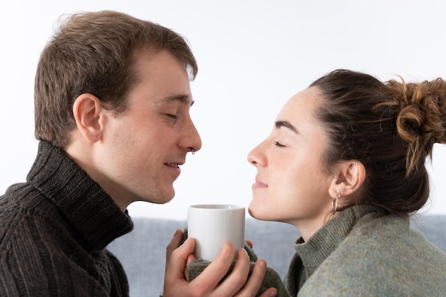 Pareja romántica oliendo y sosteniendo una taza de café caliente