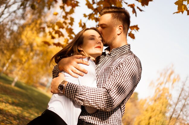 Pareja romántica en el parque de otoño - día soleado - concepto de amor, relación y citas