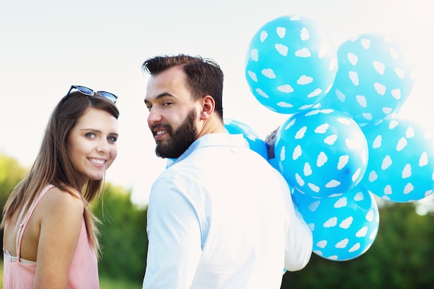 Una pareja romántica de pie afuera con globos.