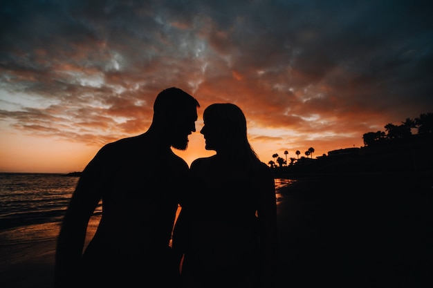 Pareja romántica en la playa en un colorido atardecer de fondo.Un chico y una chica al atardecer en la isla de Tenerife.