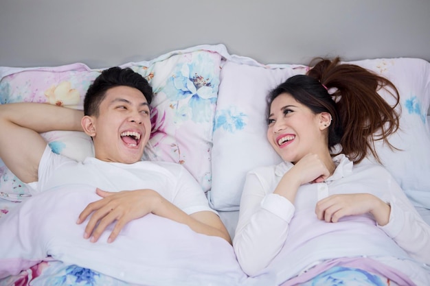 Una pareja romántica riendo juntos en el dormitorio.