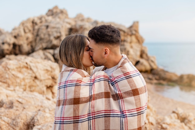 Foto pareja romántica de tiro medio con manta a cuadros