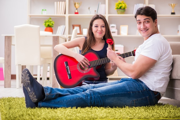 Pareja romántica tocando la guitarra en el piso