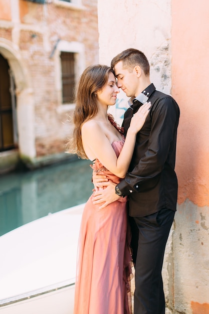 Pareja romántica en Venecia. Joven mujer y hombre en ropa elegante abrazando cerca del canal veneciano y edificios antiguos. Italia, Europa