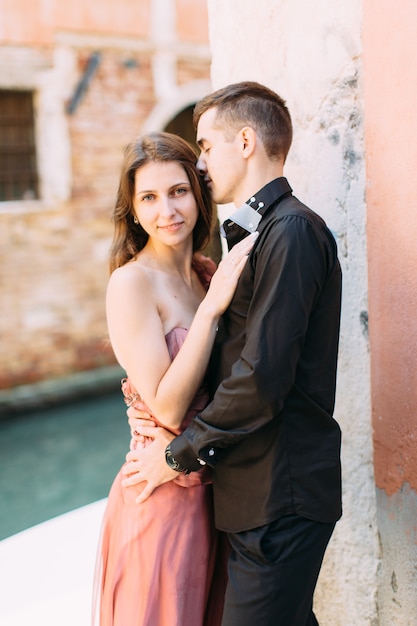 Pareja romántica en Venecia. Joven mujer y hombre en ropa elegante abrazando cerca del canal veneciano y edificios antiguos. Italia, Europa