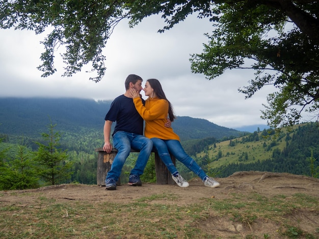 Una pareja con ropa informal se sienta bajo un gran árbol con fondo forestal