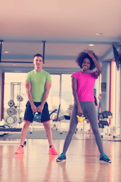 Una pareja saludable entrena con pesas levantando pesas en el gimnasio de crossfit mujer afroamericana con peinado afro