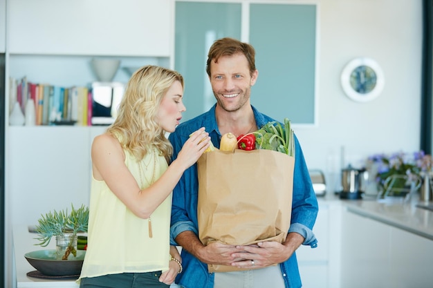 La pareja saludable es una pareja feliz Fotografía de una pareja feliz sosteniendo una bolsa llena de comestibles saludables en casa