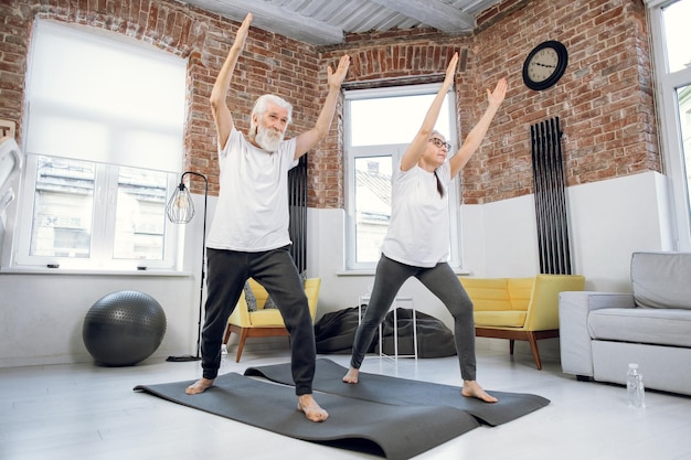 Pareja sana y activa practicando yoga en casa