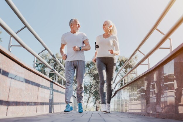 Foto una pareja sana y sonriente corriendo por la ciudad temprano en la mañana.