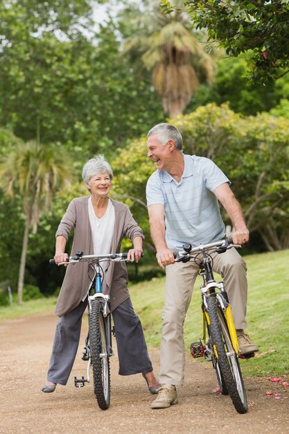 Pareja senior alegre en ciclo paseo en campo