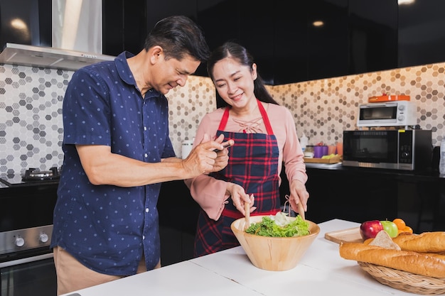 Pareja senior asiática disfruta cocinando en la cocina en casa