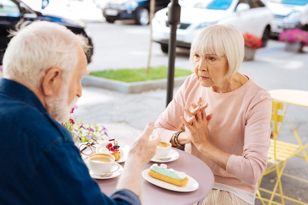 Pareja senior concentrada hablando y visitando cafe