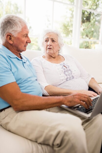 Pareja senior enfocada usando laptop en casa