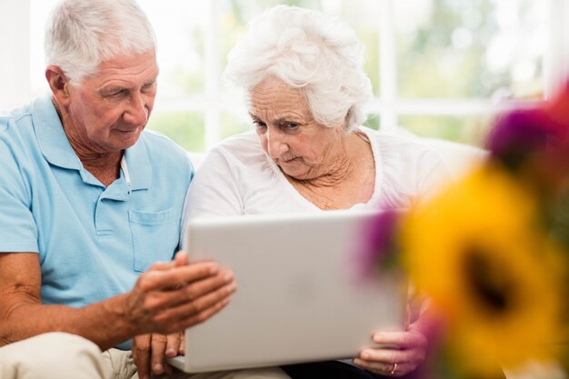 Foto pareja senior enfocada usando laptop en casa