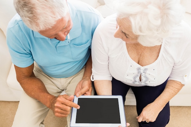 Foto pareja senior enfocada usando tableta en casa