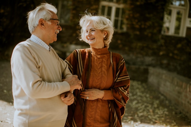 Pareja senior guapo caminando en el parque otoño