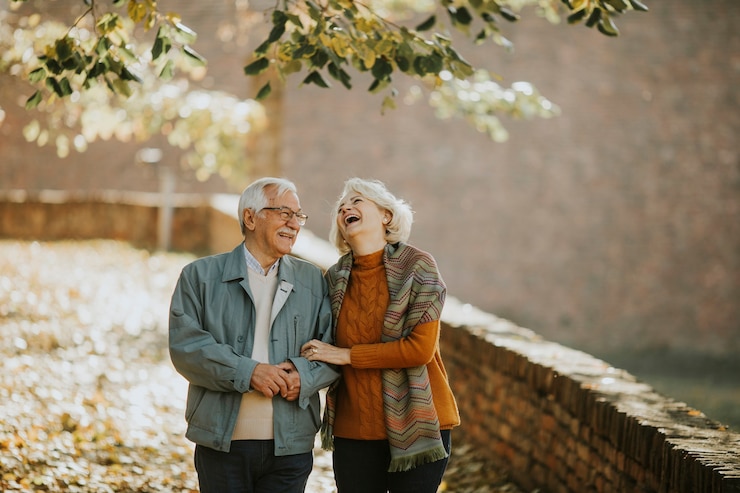 Foto pareja senior guapo caminando en el parque otoño