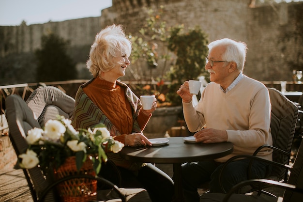 Pareja senior saludable tomando café en la cafetería al aire libre en un soleado día de otoño