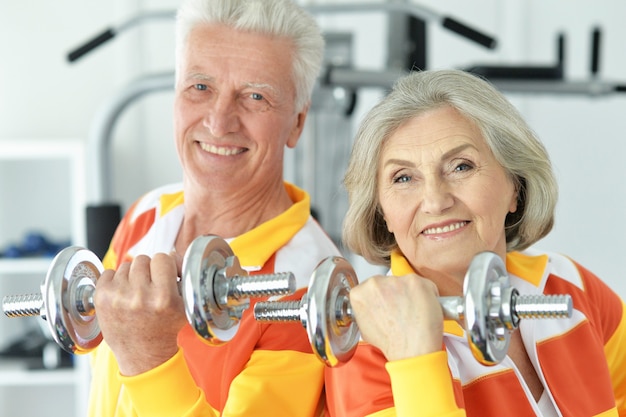 Pareja senior sonriente activa ejercicio en el gimnasio