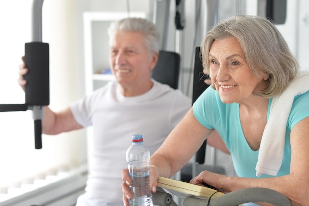 Pareja senior sonriente activa haciendo ejercicio en el gimnasio