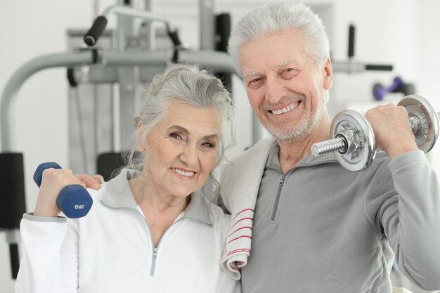 Pareja senior sonriente activa haciendo ejercicio en el gimnasio