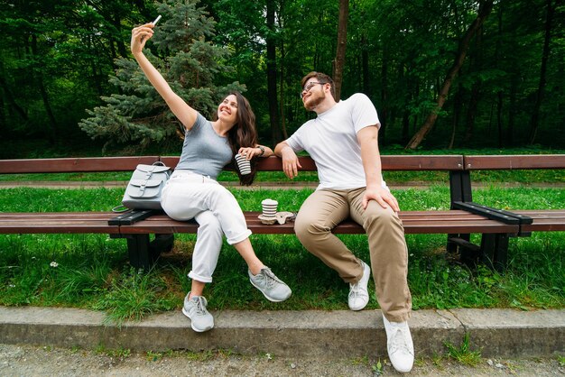 Pareja sentada en un banco hablando y bebiendo café en el parque