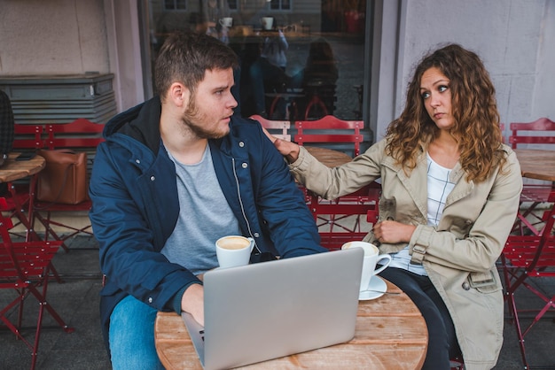 Pareja sentada en café hombre trabajando en laptop mujer es aburrida