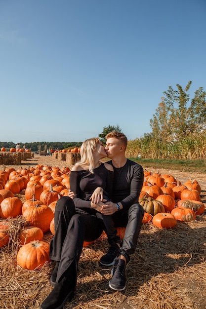 Pareja sentada en el campo cerca de calabaza, concepto de halloween. Pareja joven cerca de calabaza, tiempo de otoño.