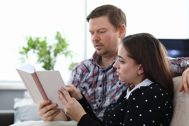 Pareja sentada en casa y leyendo un libro juntos