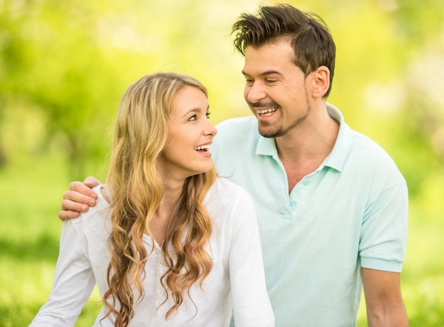 Pareja sentada en el césped en el parque de verano.