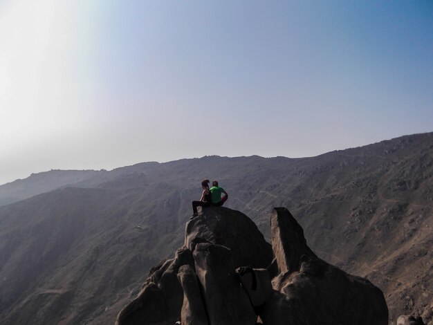 pareja sentada en la cima de una montaña